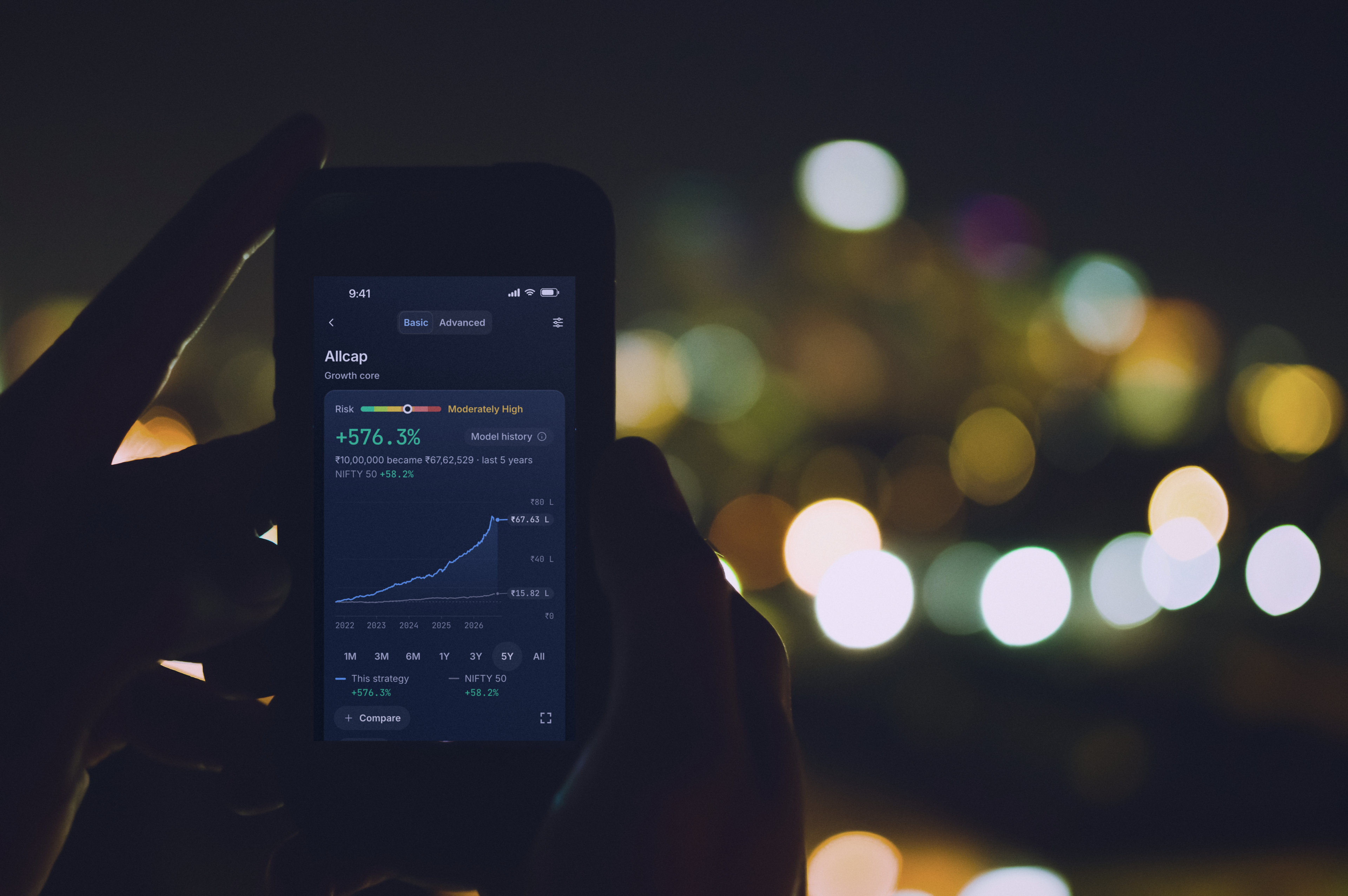 Hands holding a phone against city lights at night, a RupeeCase strategy on screen