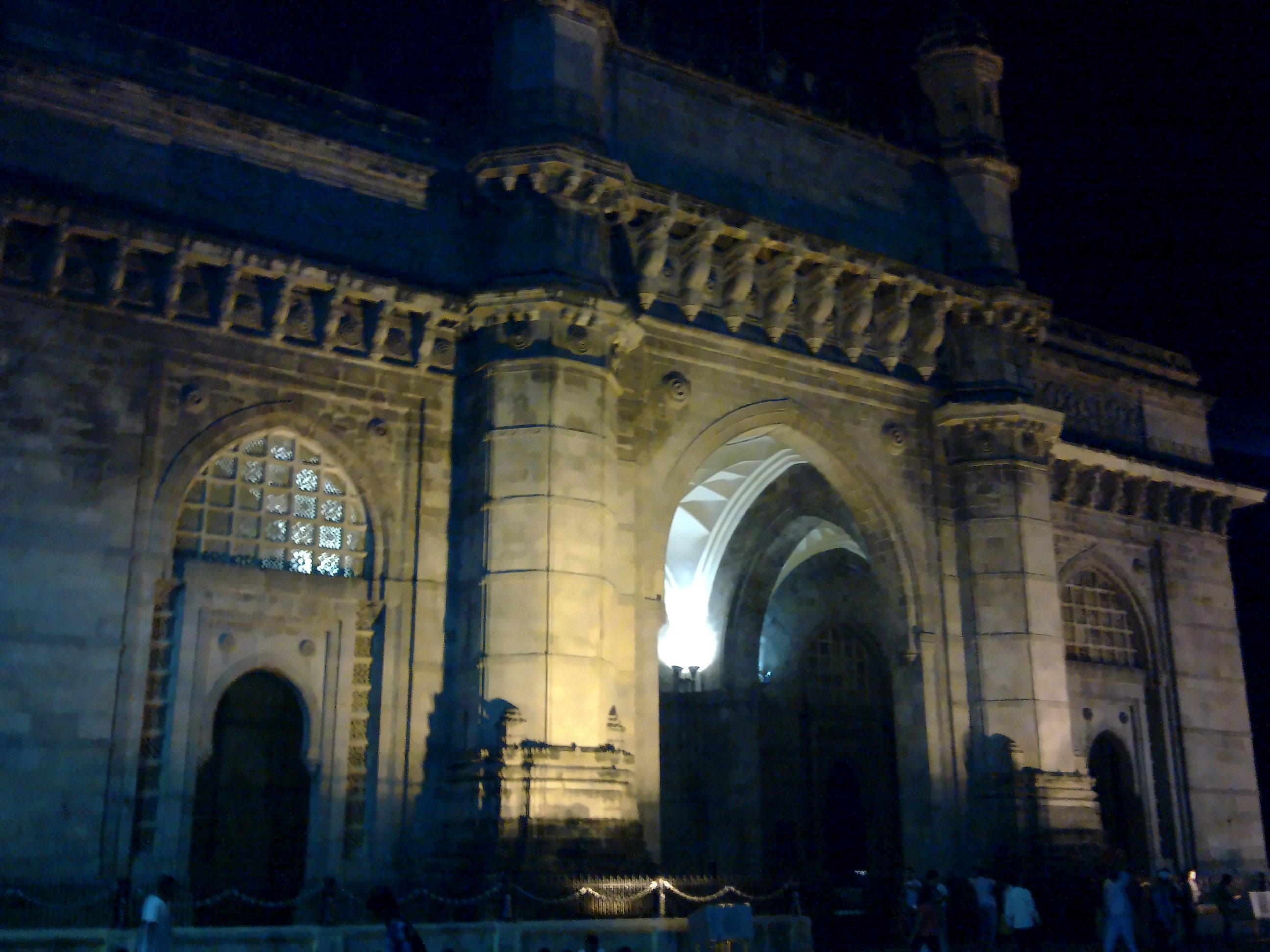 The arches of the Gateway of India lit against a dark blue night sky