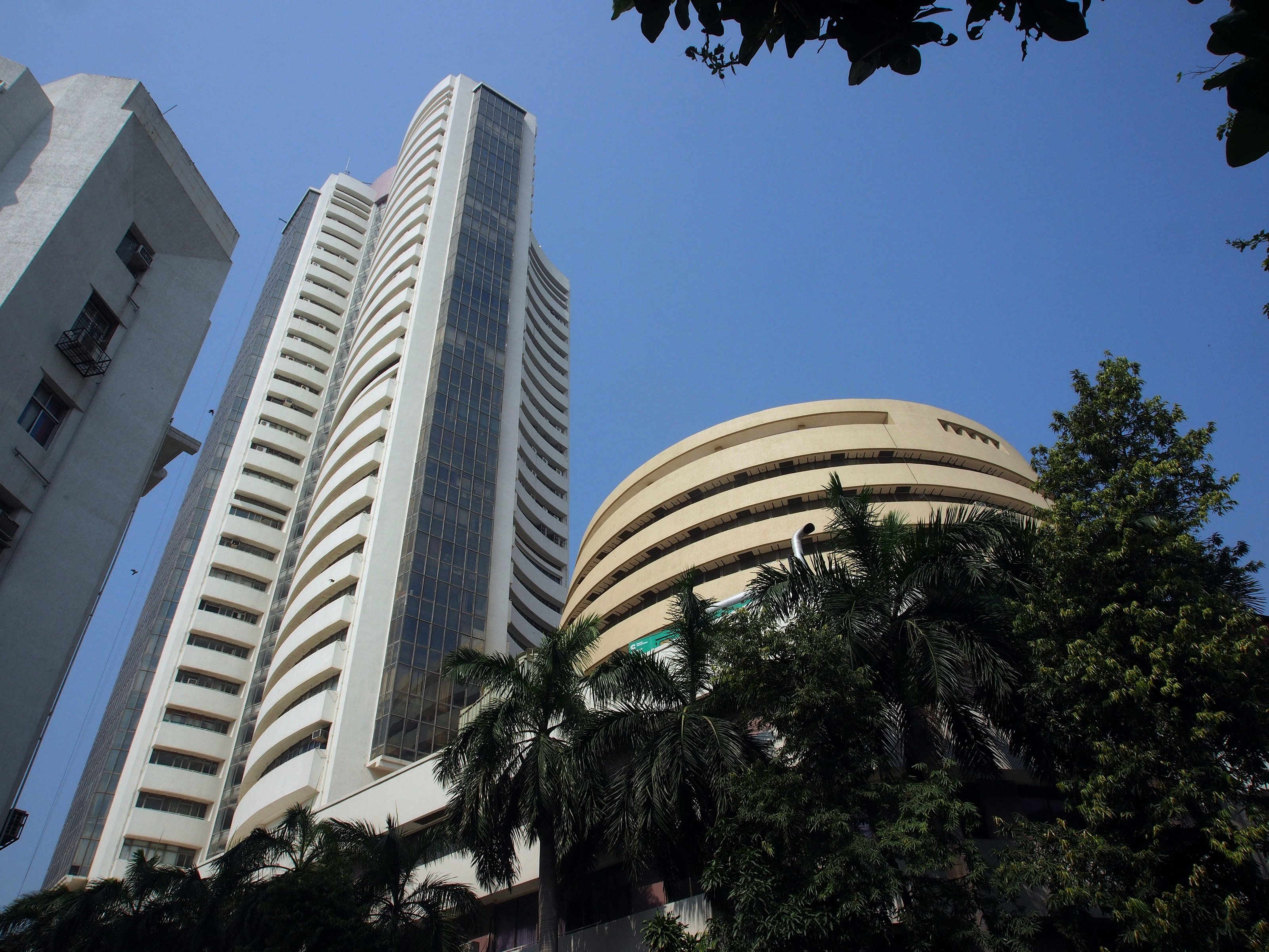 Phiroze Jeejeebhoy Towers and the BSE rotunda on Dalal Street, Mumbai, against a clear blue sky, palms in front